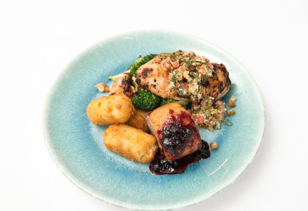 chicken, duck and croquettes on elegant blue plate