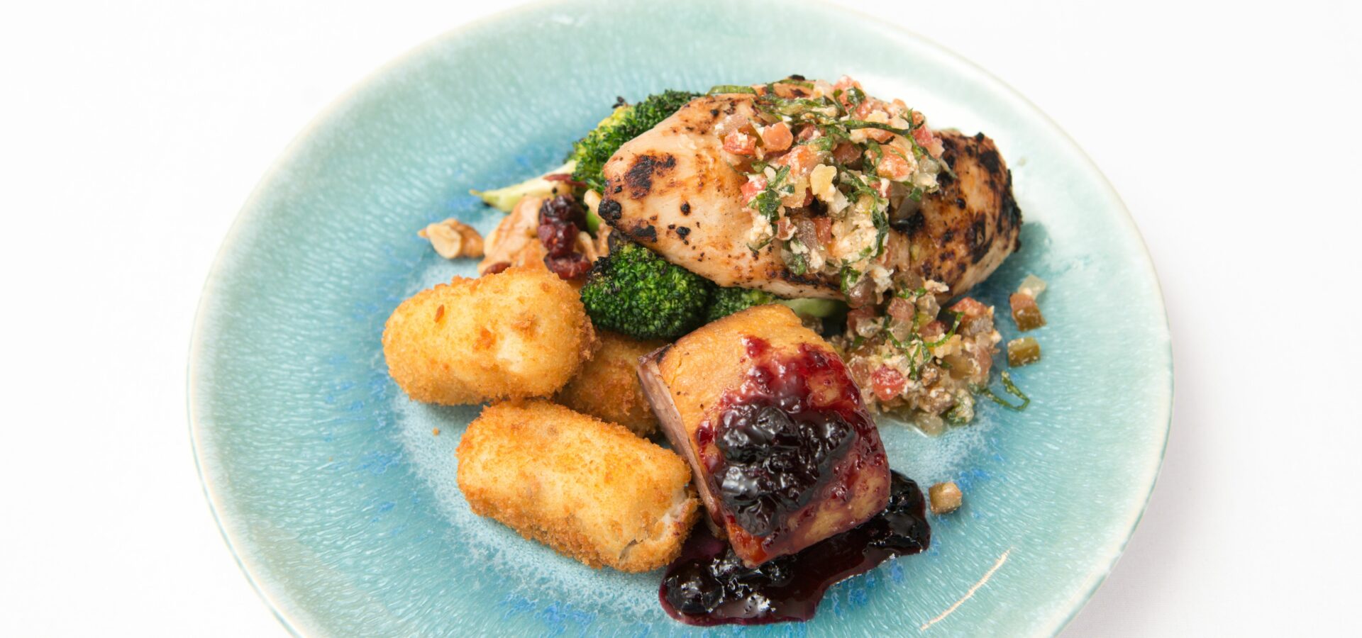 chicken, duck and croquettes on elegant blue plate