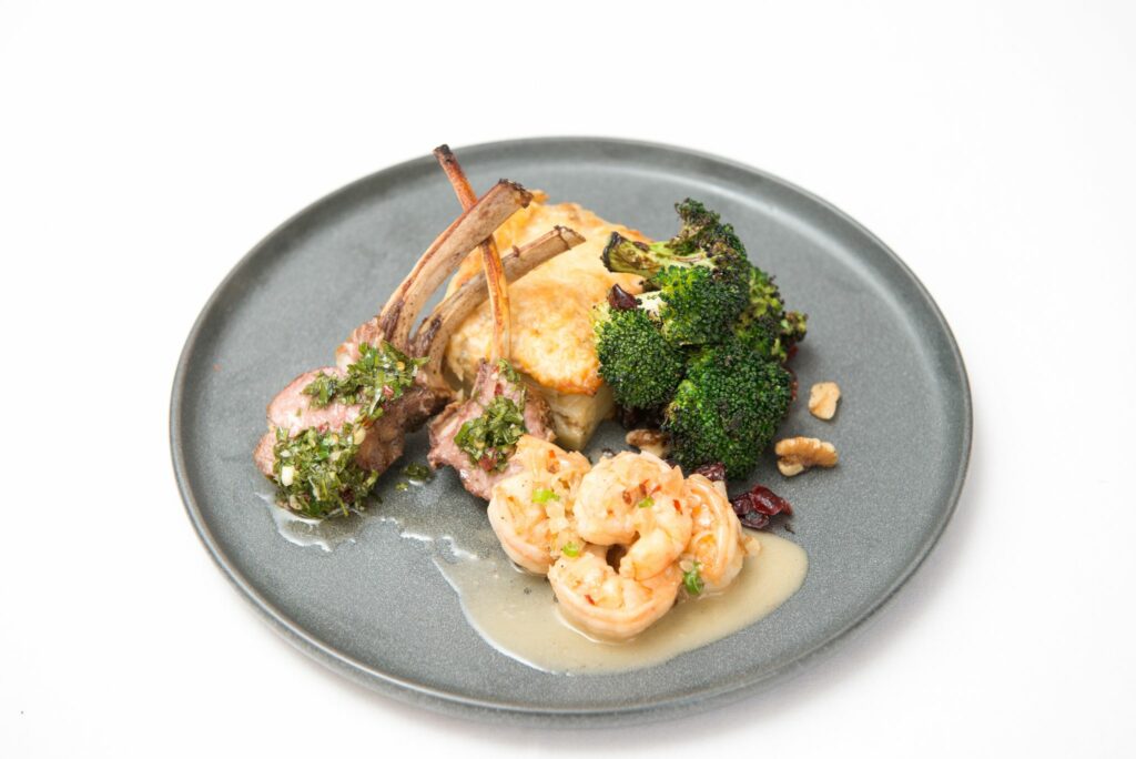 lamb chops, shrimp and broccoli on gray plate