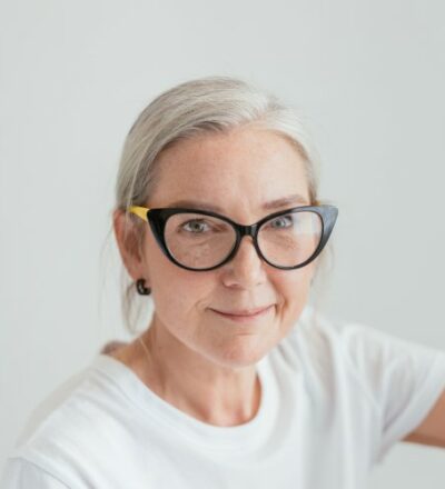 middle aged woman with black bold glasses and white tee