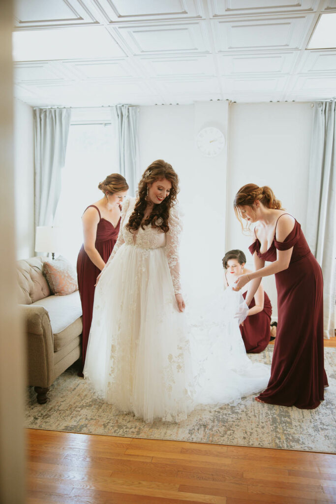 bride in dress with helpers around her