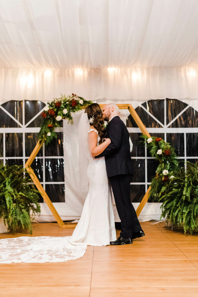 bride and groom first kiss in white tent at night